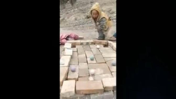 Chinese village children play pool on table made of bricks