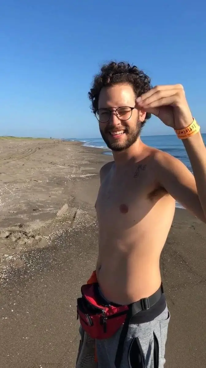Man plays with a crab at a beach in Nautla, Mexico using his hand's shadow